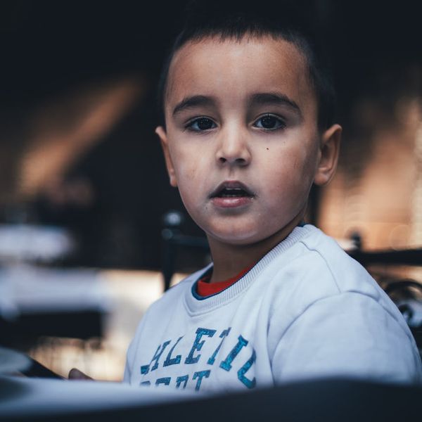 Child sitting in lotus pose with eyes closed, imagining a story.